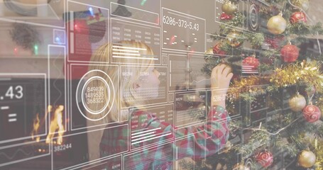 Naklejka premium Reaching plaid-shirted boy placing red ornament on Christmas tree at home, HUD panels and fireplace