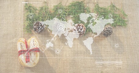 Displaying white world map overlay on burlap, with conifer sprigs, pinecones, ribboned heart-cookie