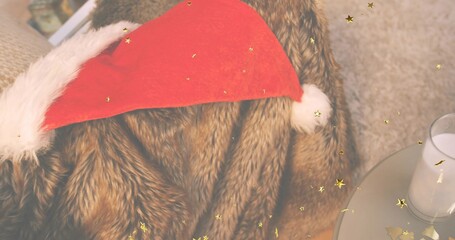 Resting red Santa hat on brown fur throw at sofa, with gold confetti and clear glass