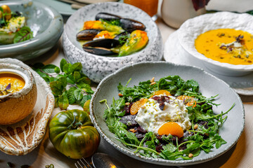 Fresh food served in a restaurant with salad, soup, and seafood on the table. Dishes of salad, soup, and seafood are arranged on a table in a restaurant setting
