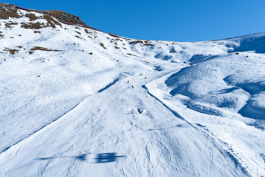 View of skiers descend a pristine, snow-covered mountain under a clear blue sky, the crisp air biting at exposed skin, Avoriaz 1800, Auvergne-Rhone-Alpes, France.