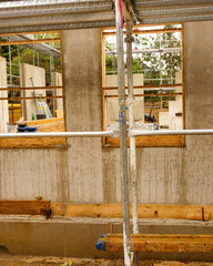 Construction of a building with scaffolding and walls in progress at a worksite in a rural area during daylight hours