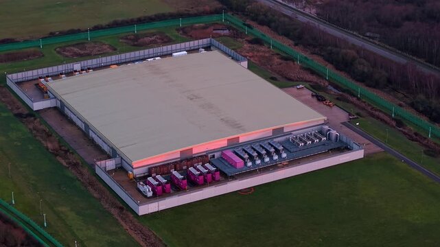 Aerial view of the Lloyds Horizon Data Centre, with its large building and colorful power units contrasting against the green grass, Corby, United Kingdom.