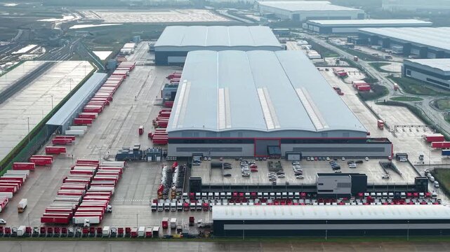 Northampton, United Kingdom - 17 January 2026: Aerial view of the Royal Mail Midlands Super Hub with rows of red trucks contrasting against the grey buildings.