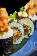 Close-up of Crispy Shrimp Tempura Sushi Roll with Creamy Sauce and Green Onions.