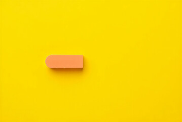 A single peachcolored eraser on a bright yellow background  simple office supplies still life