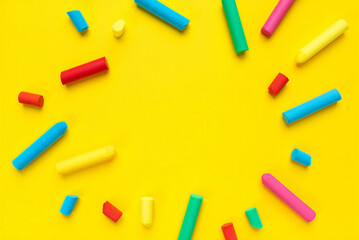 Colorful chalks scattered on bright yellow background for creative art and education  school supplies