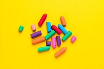 Colorful chalks scattered on yellow surface for drawing and writing  various shapes and sizes included