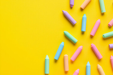 Colorful pastel chalks scattered on bright yellow background for art and education purposes  various hues of pink blue green purple