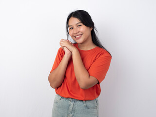 Young beautiful Asian woman wearing orange t-shirt over white background hugging herself happy and positive, smiling confident. Self love and self care