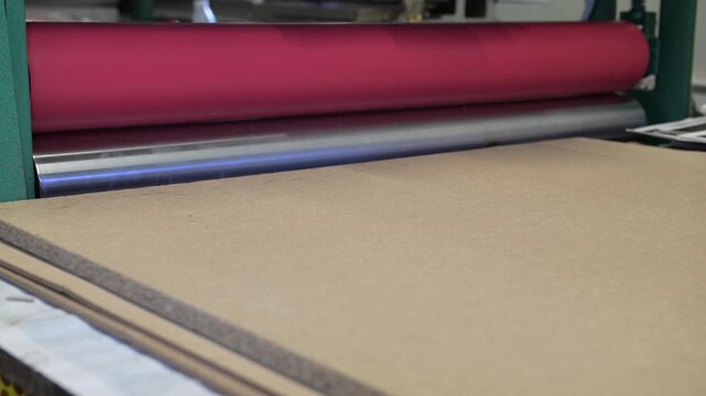 The rotating shafts of the industrial laminator in the printing house let posters through. Mechanics of rotation of metal shafts. Working hands at the machine