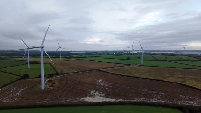 Aerial view of wind turbines standing tall amidst the patchwork fields, creating a stark contrast against the moody sky, Yelvertoft, Crick, United Kingdom.
