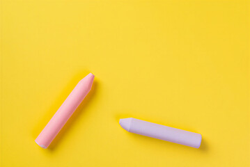 Two colorful chalks on bright yellow background for drawing and art projects  educational supplies