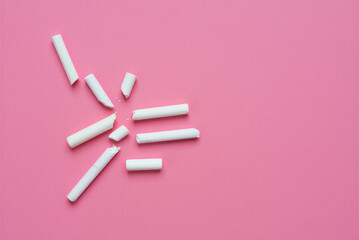White broken pieces of chalk scattered on pink surface for drawing or writing artistic designs and educational purposes at home or school
