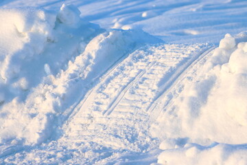 A snowmobile track in the snow at the side of the road