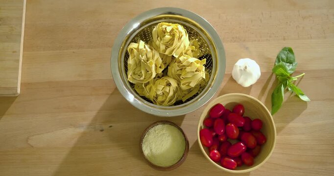 Overhead camera filming colander holding three pasta nests while lighting shifting for recipe prep