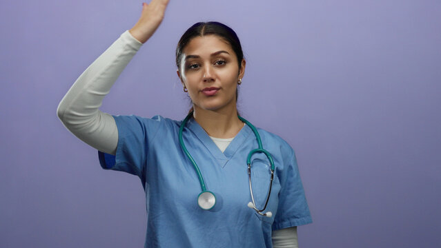 Hispanic woman nurse in blue scrubs with stethoscope on purple background focused on healthcare professional presence.