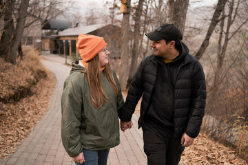 Fototapeta premium Happy young adult man and woman at walk in city park in autumn.