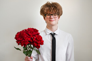 Handsome cute young man with red roses bouquet