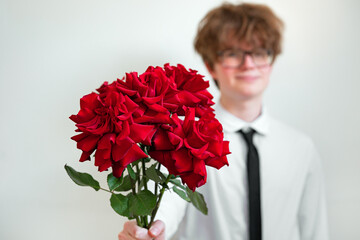Cute young man with red roses bouquet