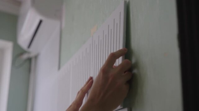 Hands applying acoustic panel to wall, soundproofing room, reducing noise, installing black and white sound absorbing material, improving studio or home acoustics, close-up. Shooting in slow motion.