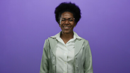 Obraz premium Woman smiling in front of an isolated purple background wearing glasses and a light green jacket exhibiting joy and confidence with a natural expression of happiness and enthusiasm.