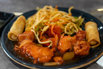 Sweet and sour pork, spring rolls, and Chinese noodles