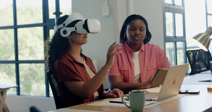African American women in office, VR user gesturing while partner tapping tablet and guiding test