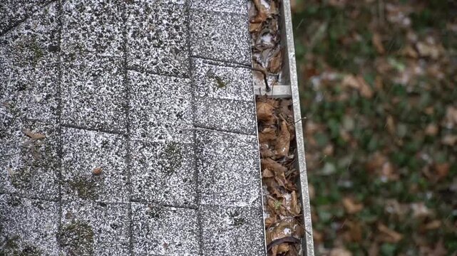 High angle close up of a grey stone tile rooftop with winter debris and dry leaves for residential architecture and roofing maintenance concepts