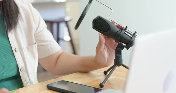 Woman's hand is reaching for mic on wooden table, rotating mount and adjusting filter to record