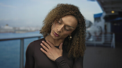 Woman clutch chest with head tilt and closed eyes outdoors on cruise deck overlooking water;...