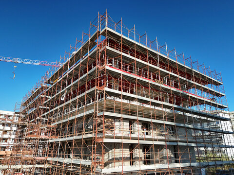 Aerial view of a construction site with a reinforced concrete structure under construction. Metal scaffolding and vertical formwork are positioned on the floor.