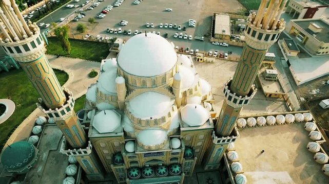 Aerial fly-cam view over the grand central dome of Jalil Al-Khayyat Mosque in Erbil, featuring intricate Ottoman architecture and minarets under a clear sky in Iraqi Kurdistan.