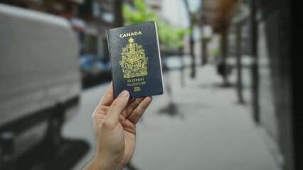 Man holding canadian passport on a bustling city street background, highlighting travel and identity verification themes outdoors. © Krakenimages.com