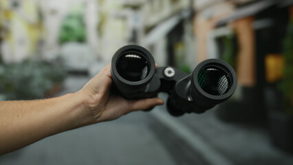 Fototapeta premium Man holding black binoculars on city street outdoor exploration adventure.