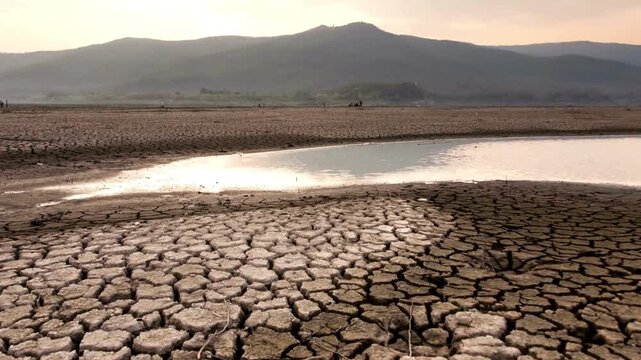 Cinematic View of Cracked Earth and Dried Lake Bed Due to Drought. relentless heat of the sun, Concept of Climate Change, Global Warming, and Water Scarcity in a Barren Landscape.