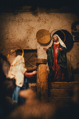 Obraz premium Traditional Christmas Nativity Scene with Virgin Mary Figurine in Rustic Setting, Religious Bethlehem Portal with Dramatic Lighting for Advent and Holy Night Concept