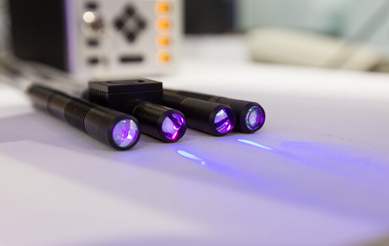 Four Purple Laser Pointers Emitting Beams in Lab Setting