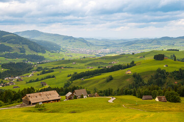 Fototapeta premium View of huts, hills and valley among Appenzell Alps mountains, Brülisau, Appenzell Innerrhoden Canton, Switzerland. Hiking concept. Rural landscape