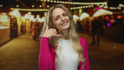 Fototapeta premium Woman lifts hand in calling pose at market, young blonde figure stands in an outdoor night street city scene.