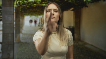 Fototapeta premium Woman pointing in a city street with a determined expression, surrounded by blurred urban background, emphasizing confidence and direct communication in an outdoor setting.