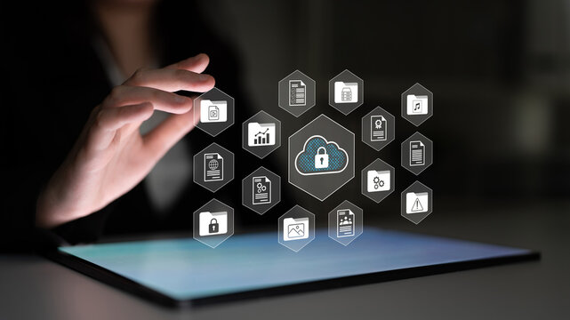 A businesswoman interacts with a tablet device displaying cloud technology icons, emphasizing data security and management in a modern digital workspace environment. Gantry - Powered by Adobe