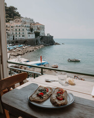 Naklejka premium An open-faced sandwich meal is on a small table on a porch with a coastal vista.