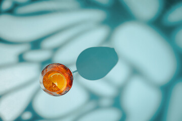 Obraz premium Summer refreshing cocktail aperol spritz on a blue background with shadows, top view