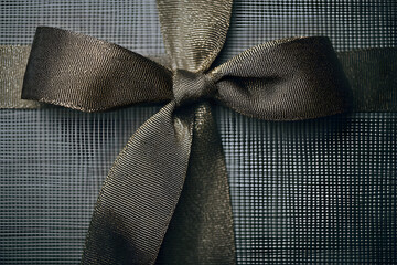 Gift wrapped in black ribbon on a textured surface ready for giving during a special occasion at a gathering
