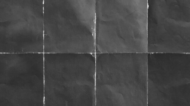 Textured black paper with fold lines showing creases and tears in close up