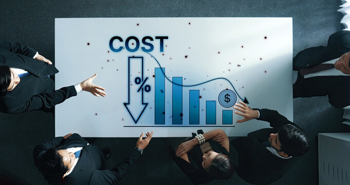 A professional business team is engaged in a discussion about cost reduction strategies, examining charts and graphs in a modern meeting room to improve financial performance. Trope