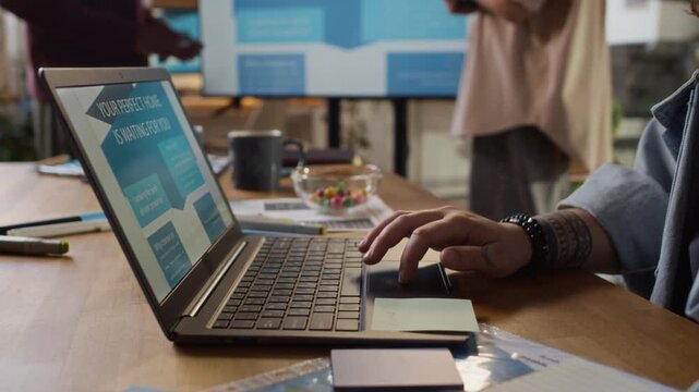 Close-up tilt-up shot of young woman using her laptop at desk while working in design bureau office