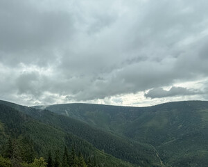 Obraz premium Moody mountain landscape with dark clouds and forested slopes