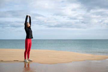 sporty woman doing stretching exercise by the sea, outdoor training